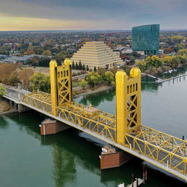 Aerial view of Sacramento River with large bridge and buildings.
